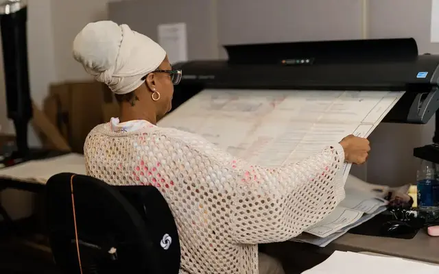 Intellinetics team member is scanning a large-format engineering drawing using a wide-format document scanner.