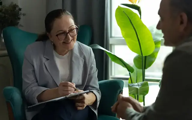 Human services professional taking notes while meeting one-on-one with a client in a private office.