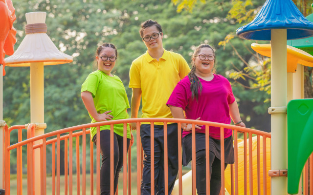 Three Kids with disabilities on a brighly colored bridge
