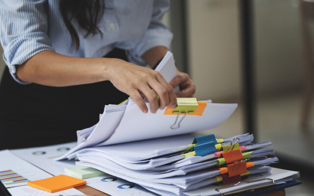 Businesswoman hands working in Stacks of paper files for searching and checking unfinished document achieves on folders papers