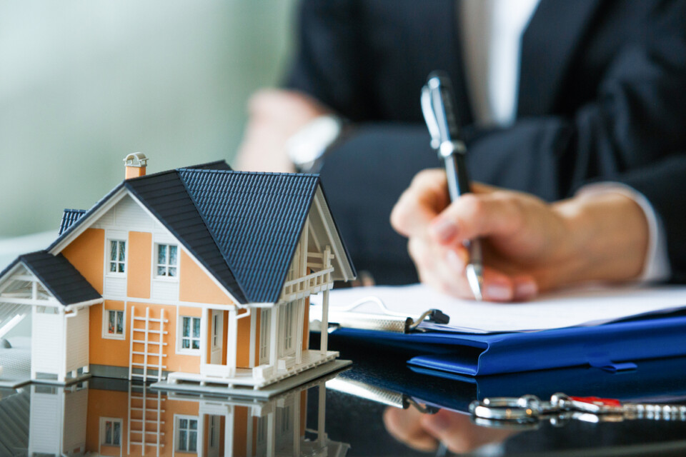 image of a hand signing a contract with a home builder