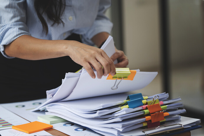 Businesswoman hands working in Stacks of paper files for searching and checking unfinished document achieves on folders papers