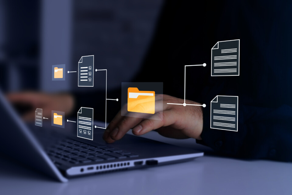Digital document and folder icons overlaid on a laptop keyboard representing document management.