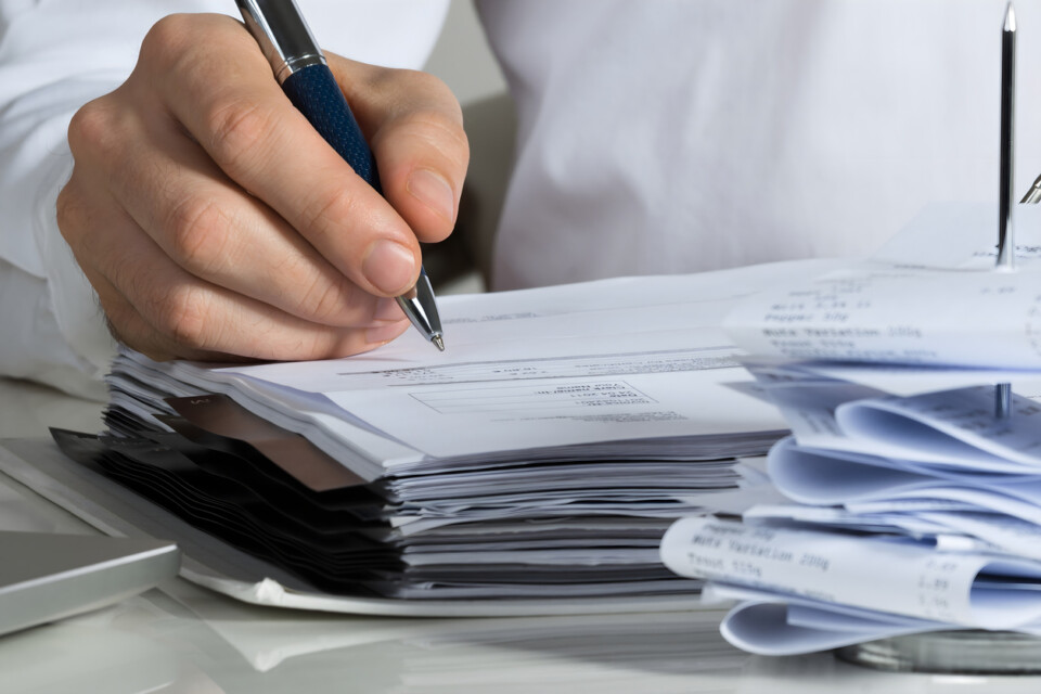 Midsection of businessman calculating invoice at office desk