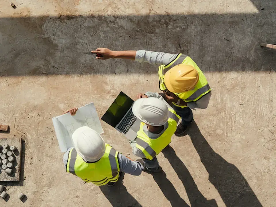 three construction workers in hard hats reviewing a jobsite