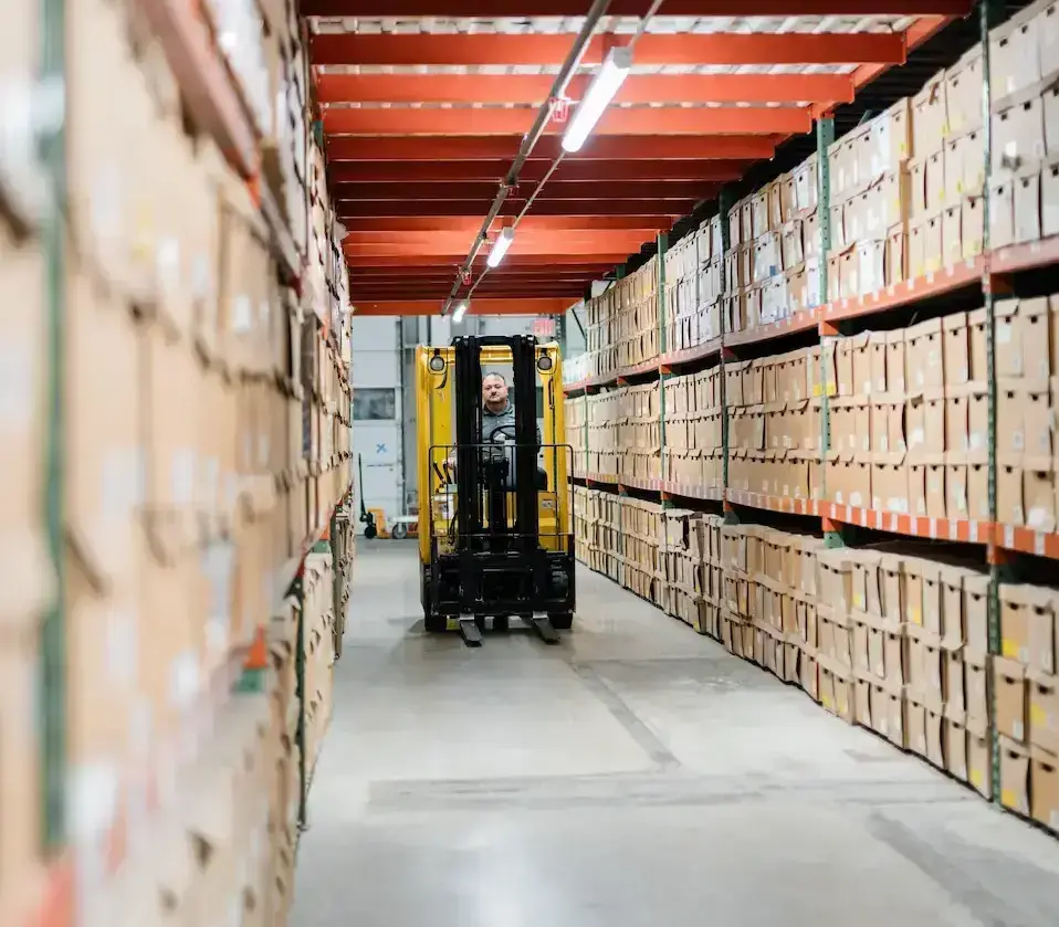 Intellinetics records storage facility with rows of organized document boxes and an employee operating a forklift.