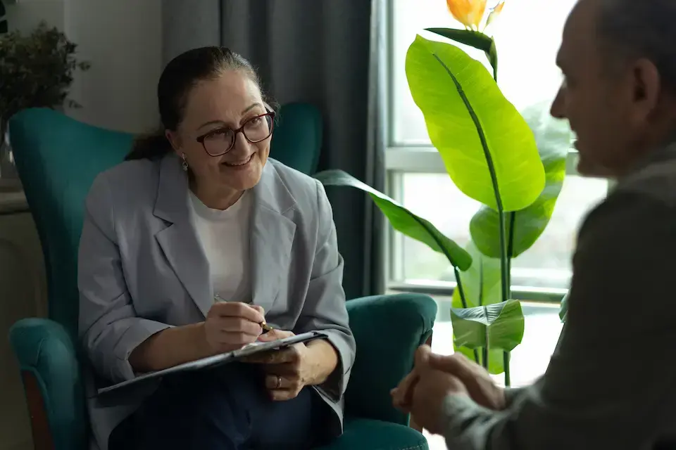 Human services professional taking notes while meeting one-on-one with a client in a private office.
