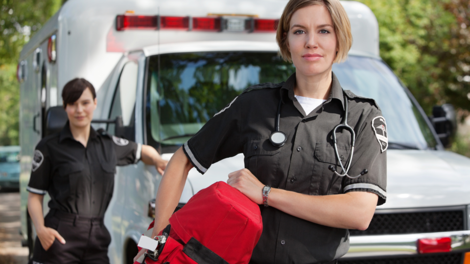 Two female first responders in front of their EMS truck