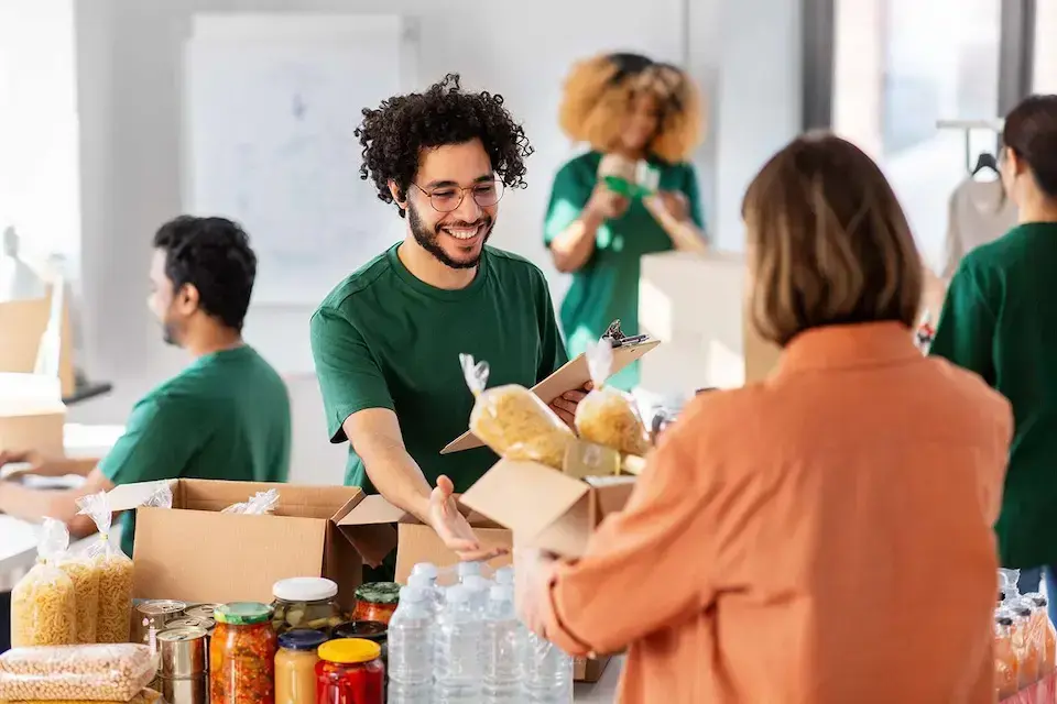 Nonprofit volunteers distributing boxes of food and supplies to a community member.