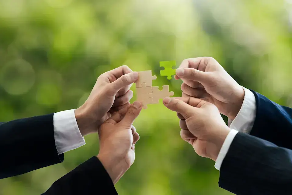 Business professionals connecting puzzle pieces, representing collaboration, integration, and strategic partnerships.