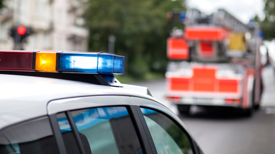 Close-up view of police car roof with lights and a fire truck in the background