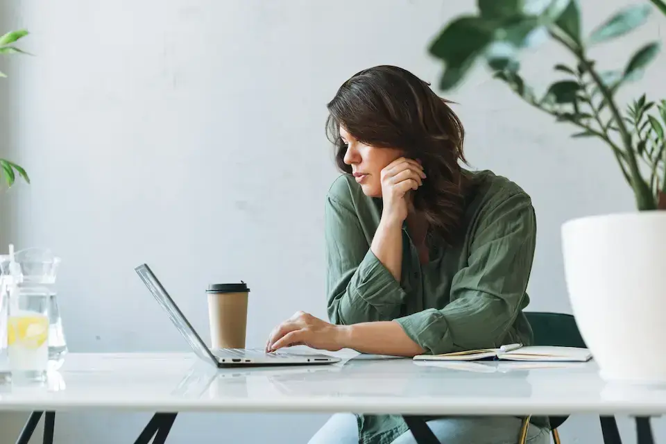 Female office professional working independently on a laptop at a bright office table.