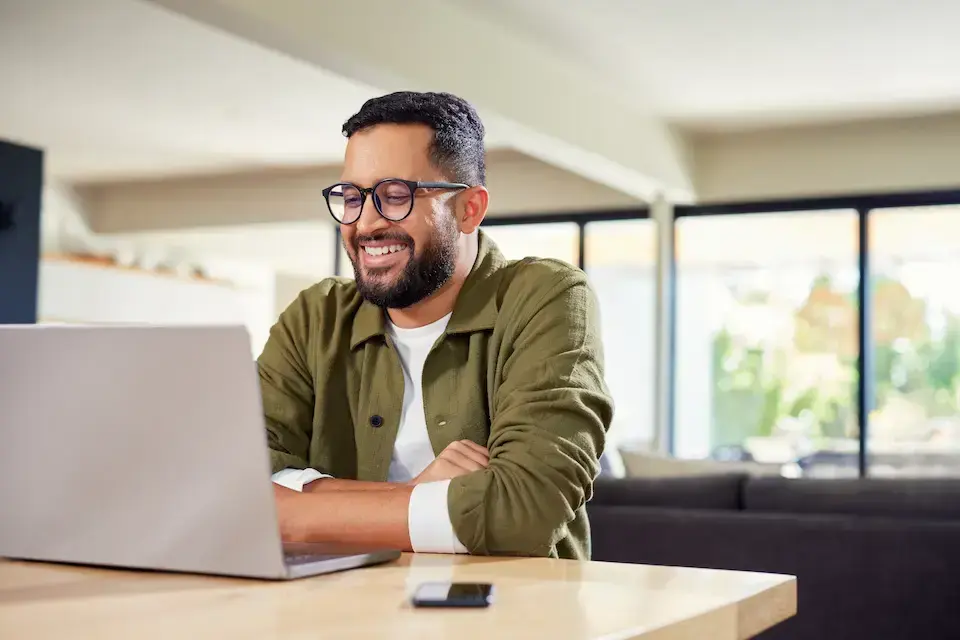 man in green shirt smiling as he works on his laptop