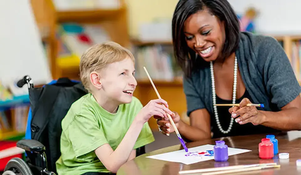 Teacher and student with disabilities painting a picture