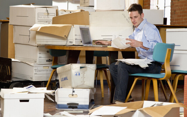 Man in an office over flowing with paperwork