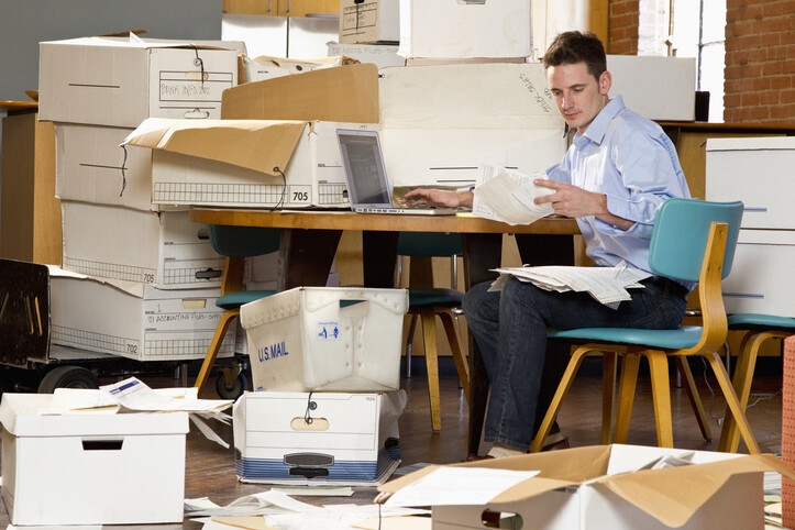 Man in an office over flowing with paperwork